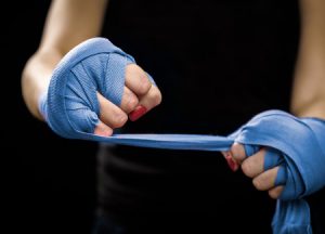 54970768 woman is wrapping hands with blue boxing wraps self defense for women isolated on black with red nai